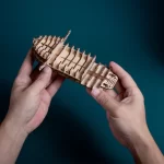 Hands holding a partially - built wooden base structure of the Fantastic Spaceship 3D Wooden Puzzle.