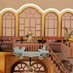 A close - up of a DIY magic book store miniature house featuring arched windows, a "Welcome" sign with book and wizard hat motifs, and a golden decorative piece.