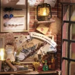 A close - up of a corner in a DIY magic wand shop miniature, showing wands, a lantern, potions, envelopes, and a "Welcome to the magical world" banner.