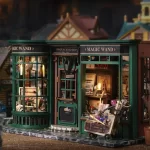 A detailed miniature of a magic wand shop with a green exterior, large windows, and a "Magic Wand" sign. Interior showcases wands, books, and other magical items.