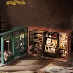 An open - view image of a DIY magic wand shop miniature house. Shows the green - hued exterior and detailed interior with shelves, cabinets, and magical items.