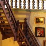 A close - up of a DIY magic book store miniature house showcasing a wooden staircase with detailed railings and a wall decorated with framed pictures.
