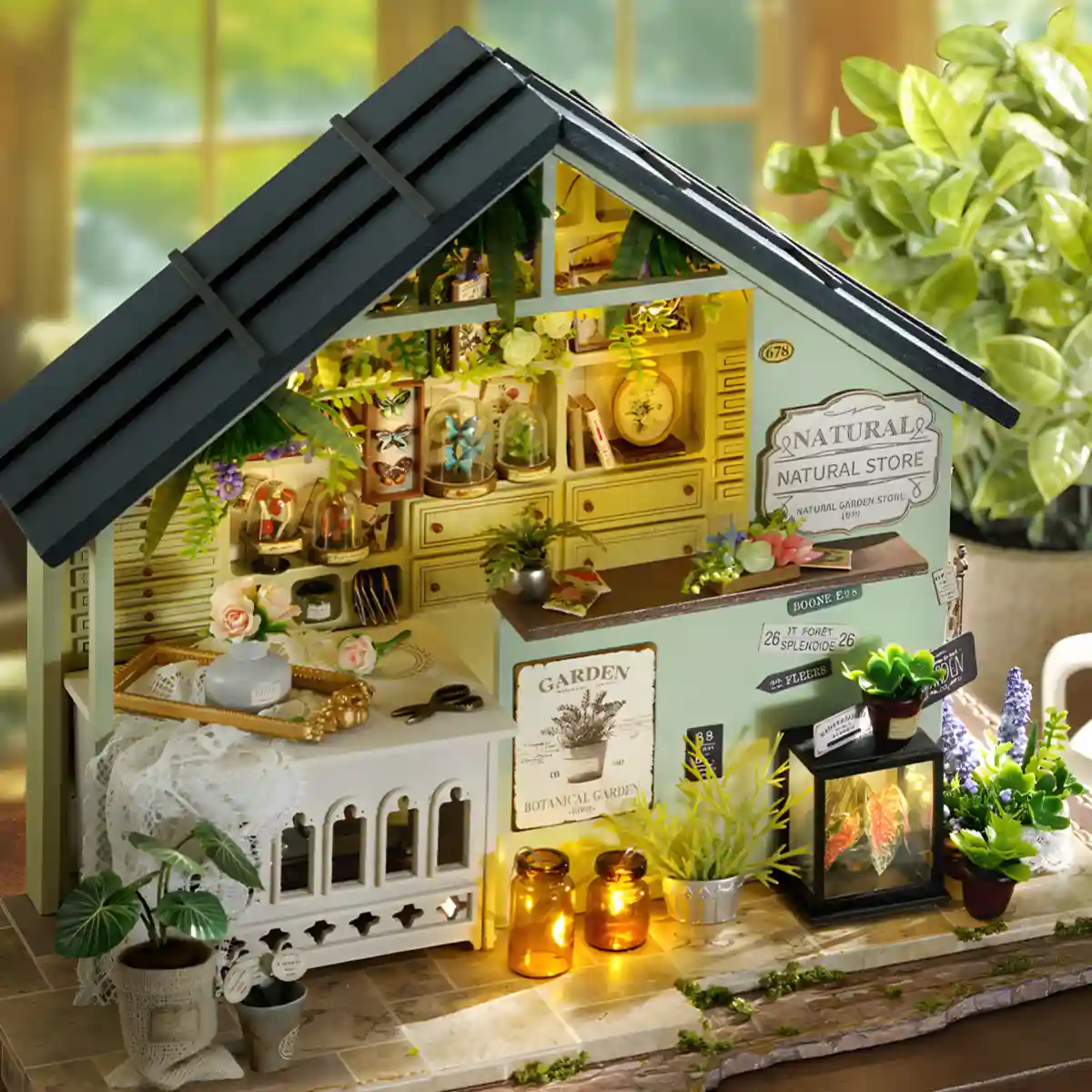 Angled view of the completed and illuminated plant dollhouse set against a blurred natural background.