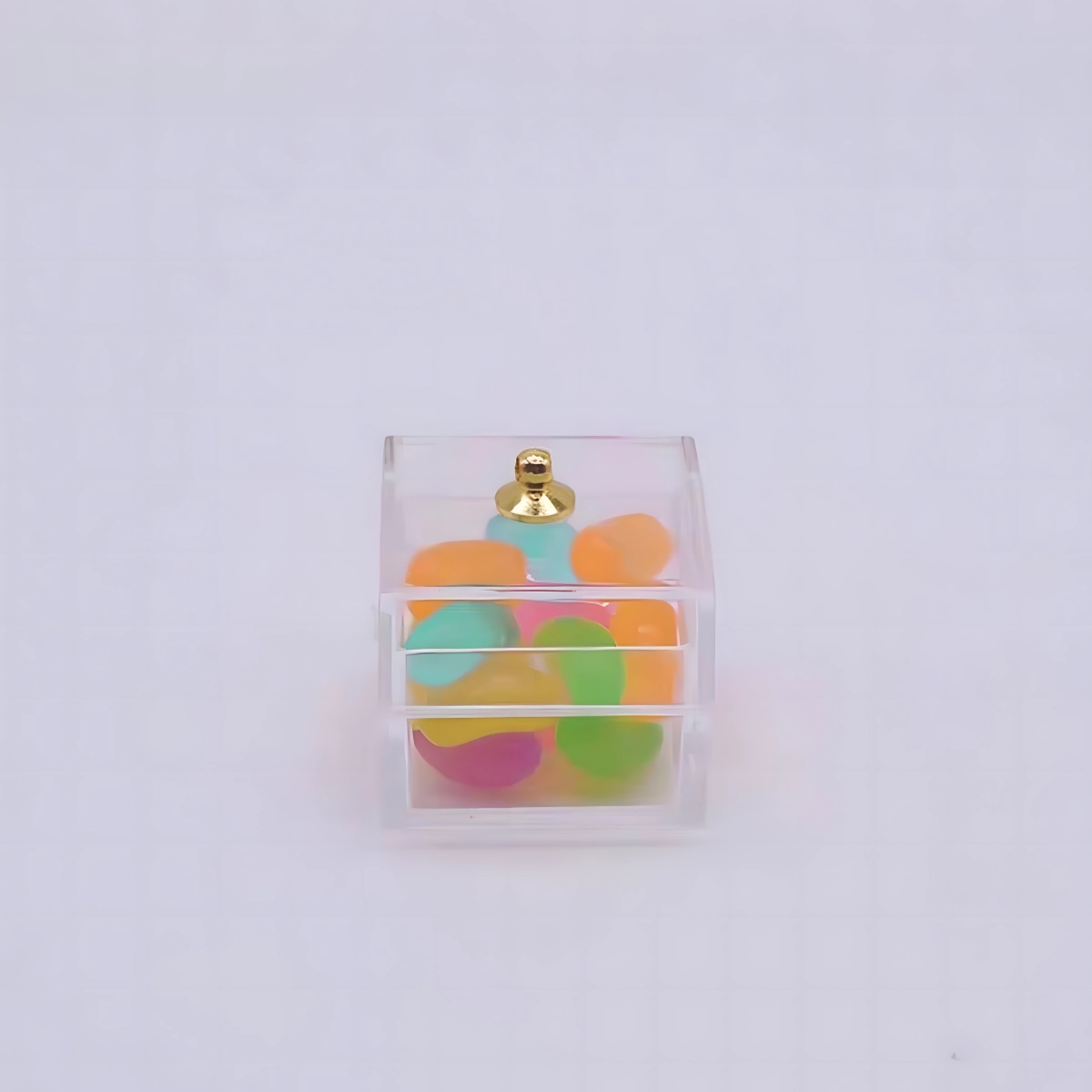 A small, clear plastic box filled with various colored miniature gummy candy beads.