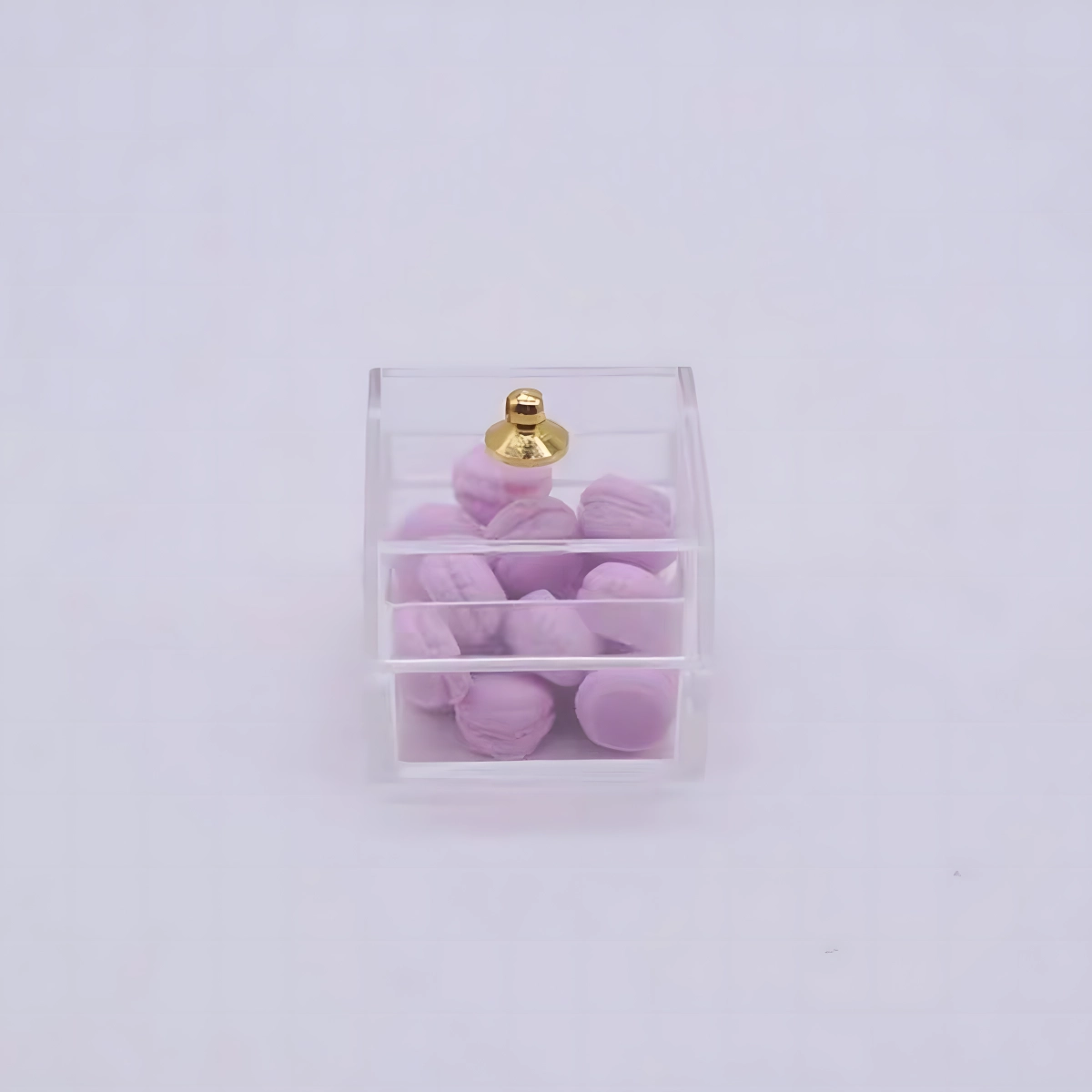 A small, clear plastic box containing tiny purple miniature macarons.
