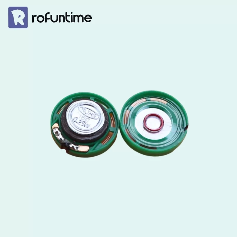Two small, round green speakers from the Mini Music Box DIY Tools set are shown side-by-side on an orange background, displaying their front and back.