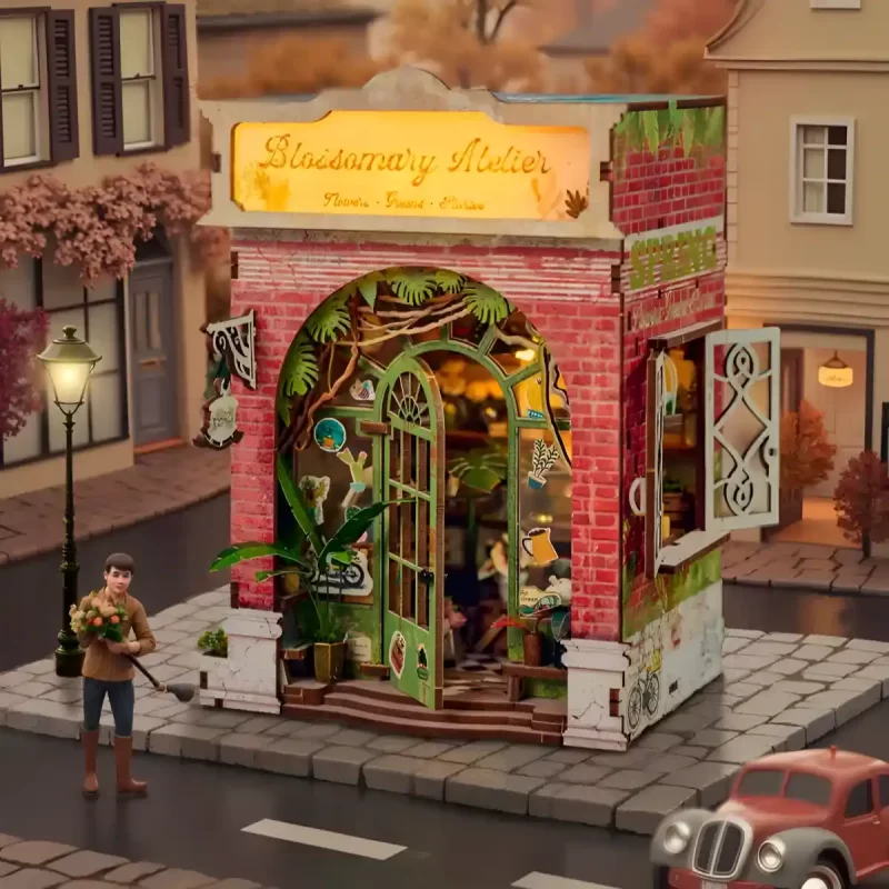 The Bloomsomary Atelier flower shop book nook model is placed in a handcrafted European-style flower book nook scene, with a small boy figurine and a vintage car model nearby.
