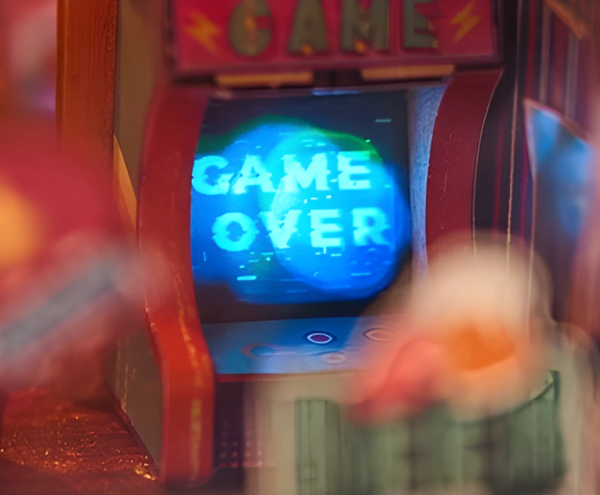A miniature arcade machine with a blue screen showing the words "GAME OVER" in a pixelated style.