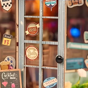 Close-up of the miniature bar model's door, showing various circular stickers and a "Cocktail Menu" blackboard.