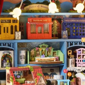Close-up of the dollhouse interior shelves, displaying miniature shops like "Traveler Cafe," "Bluebird Books," and "Teddy Bears," as well as a decorated "The Fairy Market" scene.