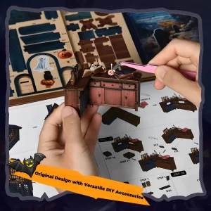 A close-up of a person's hands using tweezers to assemble a small wooden cabinet piece for the Halloween book nook kit, with instructions in the background.