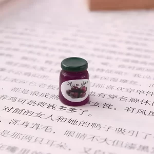 A single plum jam jar miniature, a detailed food-themed dollhouse miniature.