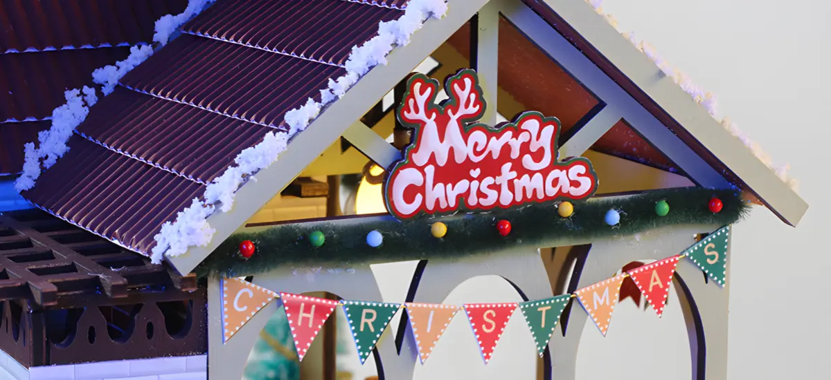 Festive miniature house with Merry Christmas sign and banner.
