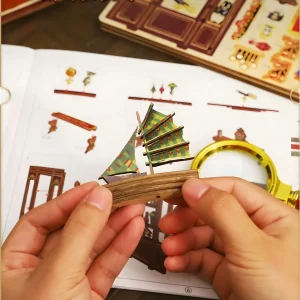 Assembling the Century Museum DIY book nook kit, holding miniature sailboat.
