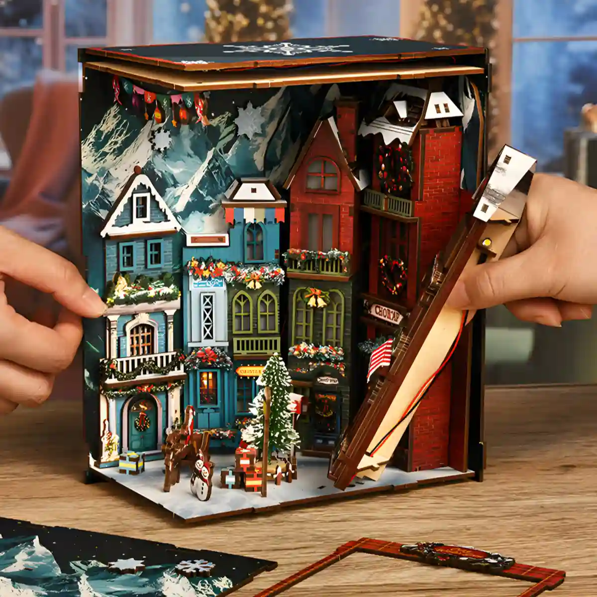 Partially assembled DIY book nook kit, showing a Christmas street corner and miniature buildings.
