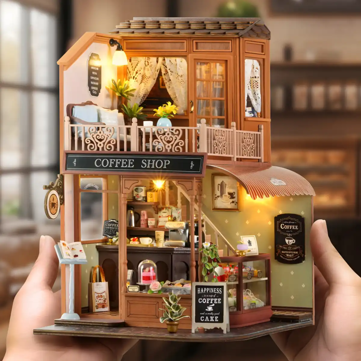 Hands holding a small DIY miniature dollhouse kit of a retro coffee shop.