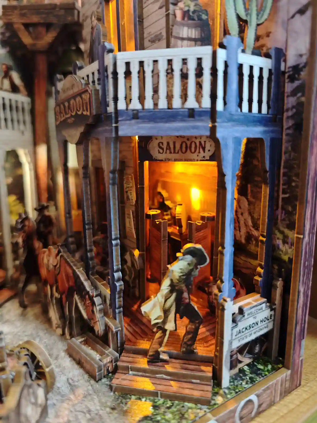 A cowboy figure entering an illuminated saloon in a detailed cowboy book nook scene.