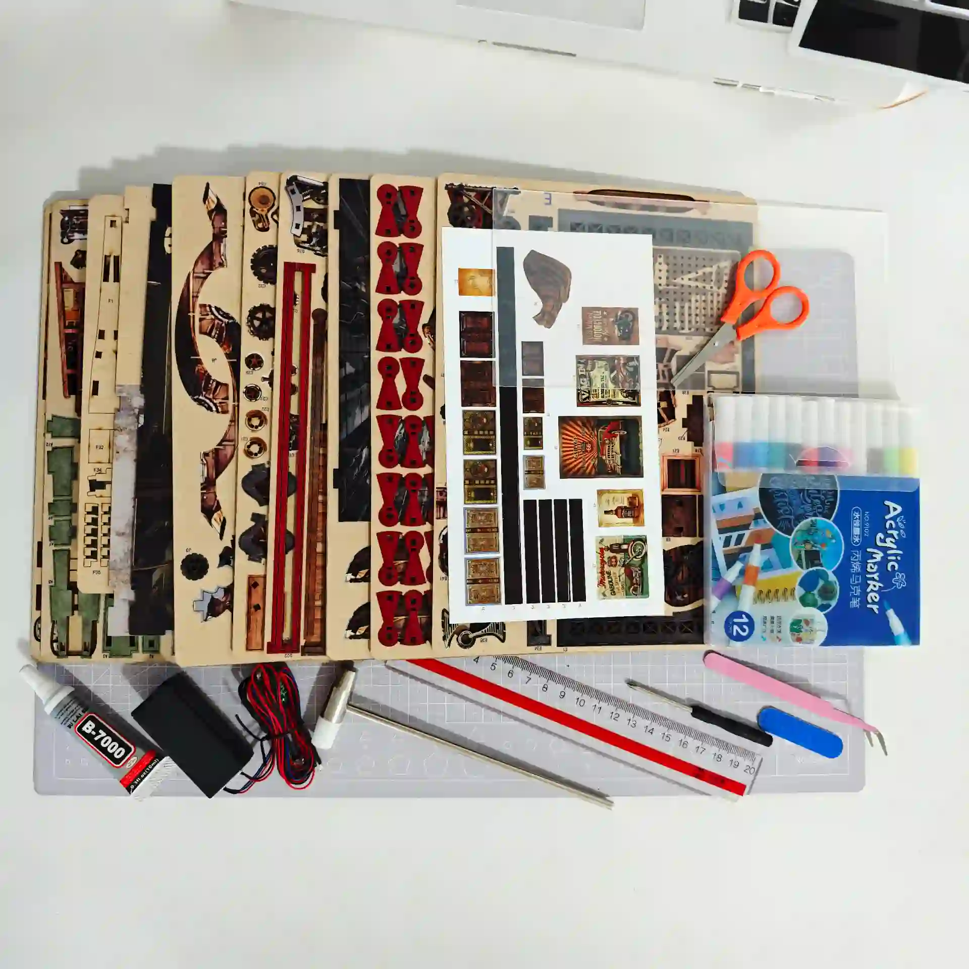 DIY book nook kit contents, with pre-cut wooden pieces, paper, glue, and craft tools.