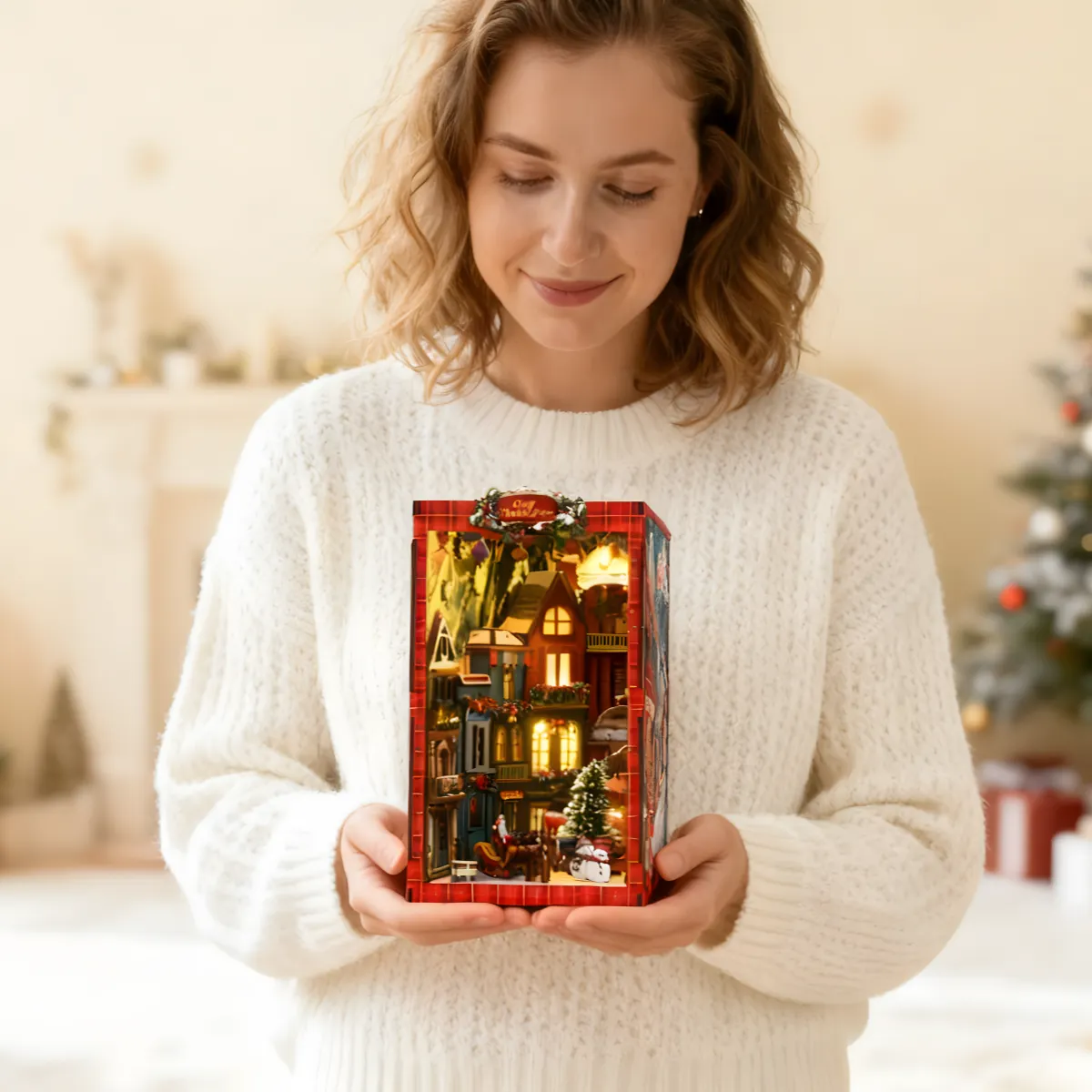 A woman holding a beautifully lit Rofuntime Christmas miniature house; a festive Christmas DIY kit perfect for holiday craft decoration.