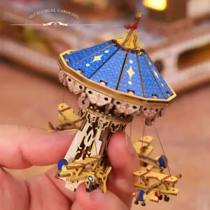 A hand holding the miniature rotating carousel puzzle with small airplanes from the Annecy Castle.