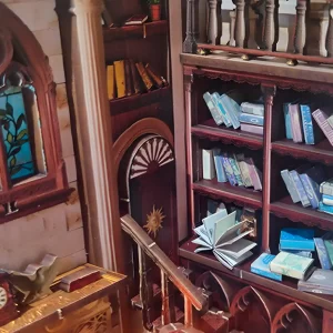 Corner view of the Athena’s Study Miniature House, winding stairs, bookshelves, and stained-glass window detail.