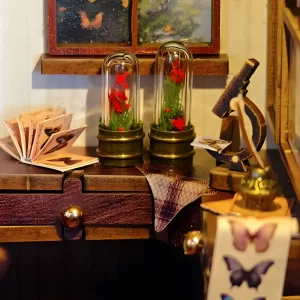 Detailed miniature desk in the countryside studio book nook, featuring flower cloches and a tiny microscope for peaceful décor.