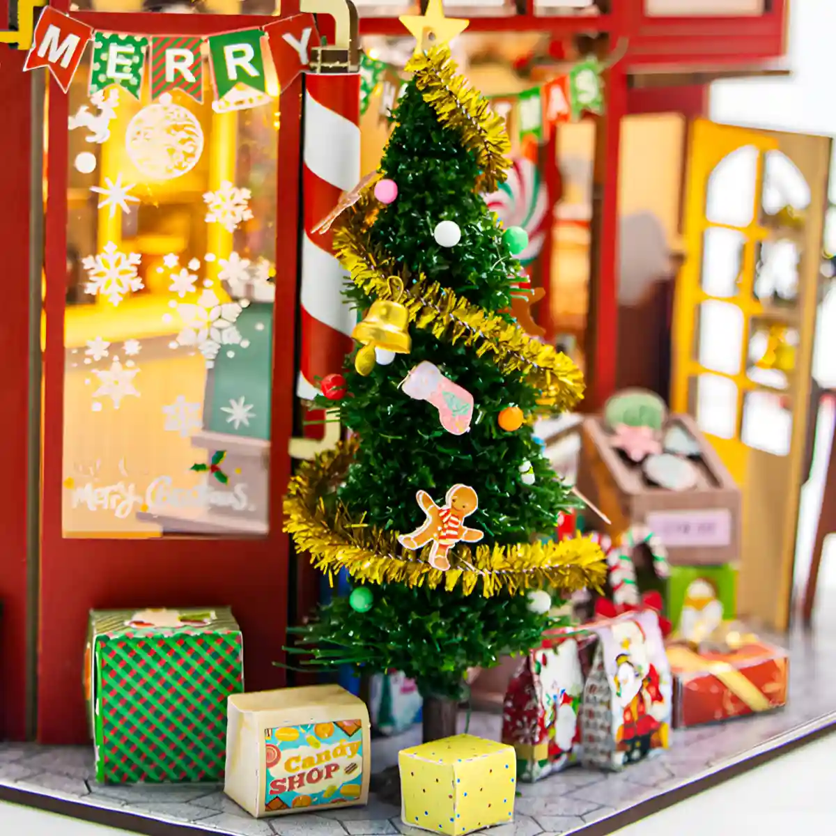 Christmas Candy House exterior with a decorated tree, gift boxes, and a "MERRY" banner.