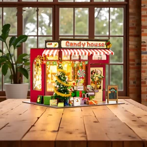 Lit-up Christmas Candy House dollhouse displayed on a wooden desk as a cozy Christmas gift.