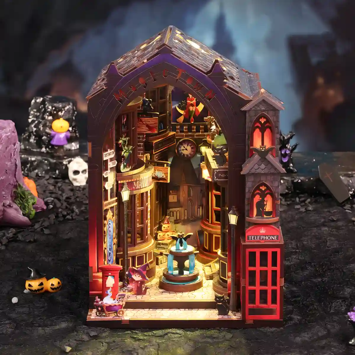 A front view of the illuminated Magic Alley DIY Book Nook Kit, showcasing the detailed secret alley with its charming wizard shops and fountain.