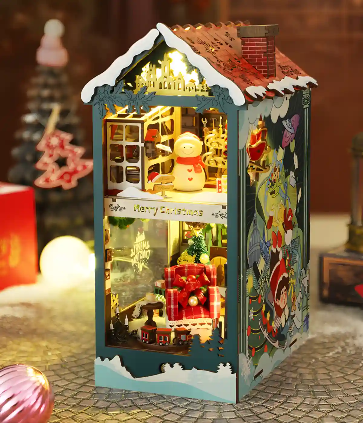 Side view of illuminated Merry Christmas DIY Book Nook Kit, showing interior scenes.