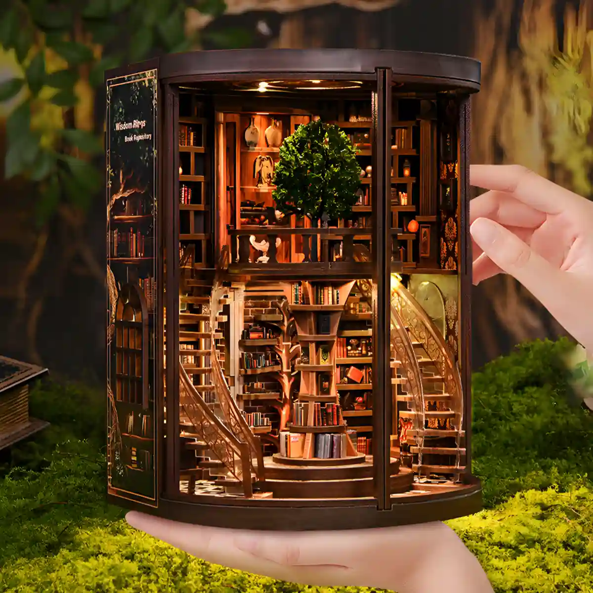 Hands holding the illuminated Wisdom Rings Bookstore book nook, demonstrating its compact size and detail.