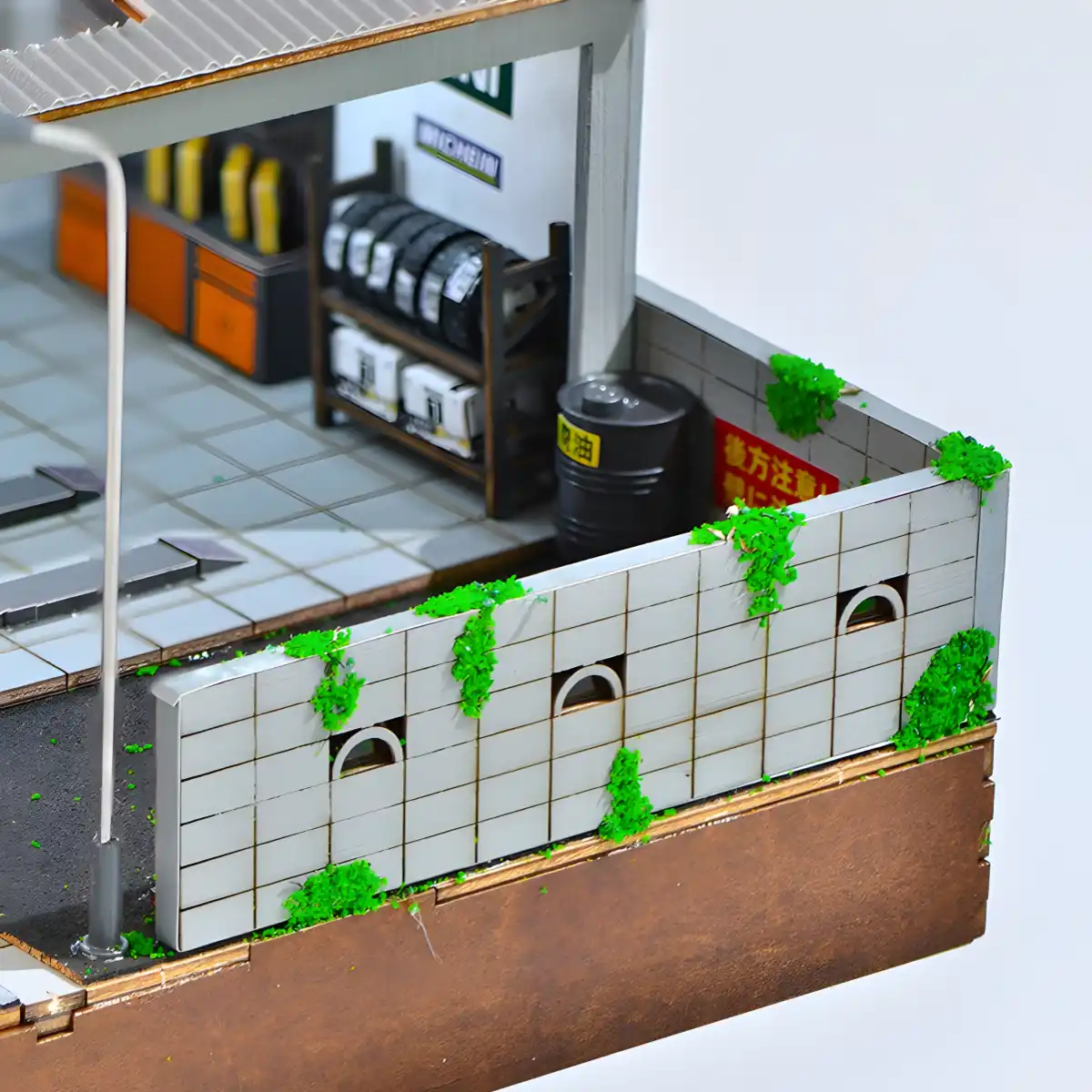 Detail of Yamada Auto Repair Shop exterior wall, tires, oil drum, and miniature greenery.