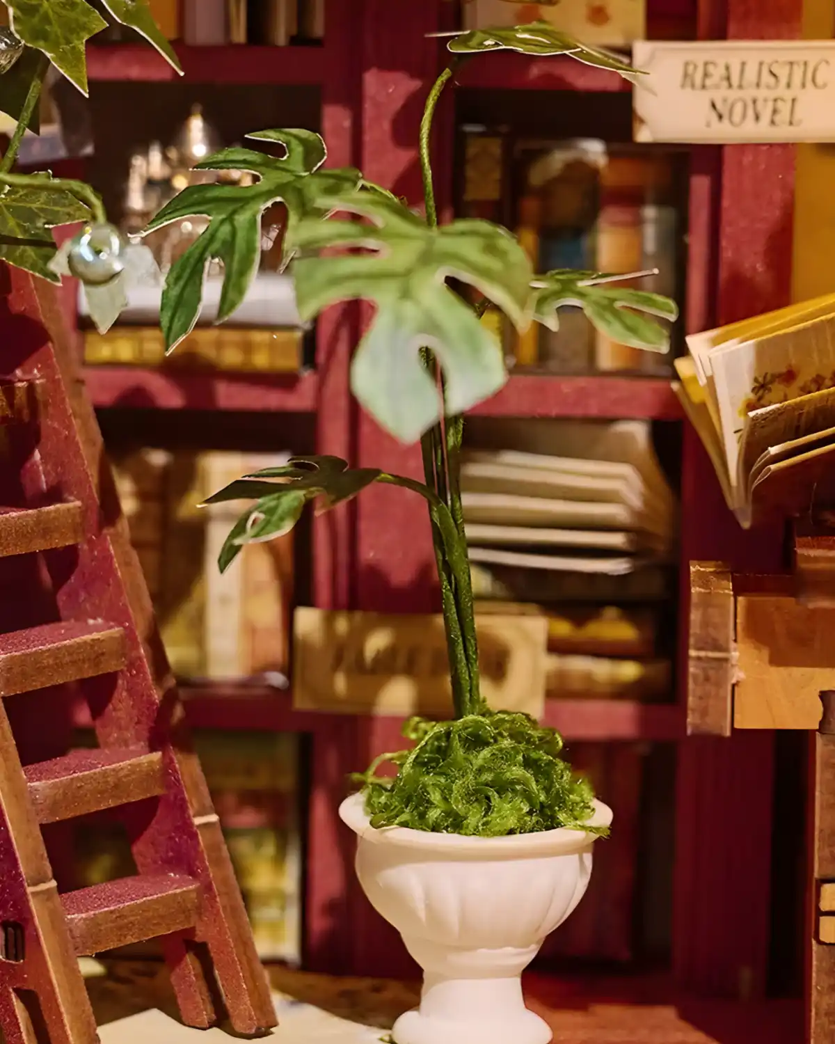 Potted green plant and red miniature ladder inside the detailed Art Bookstore book nook interior.