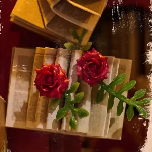 Miniature red roses and open book detail inside the Art Bookstore DIY Book Nook Kit shelf display.