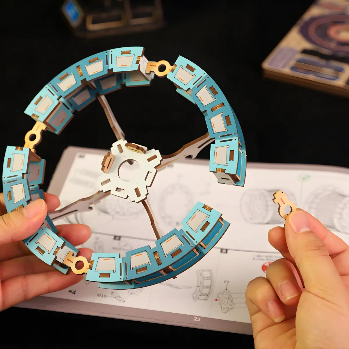 Hands assembling a circular antenna component for the Celestigon Station 3D Wooden Puzzle on instructions.