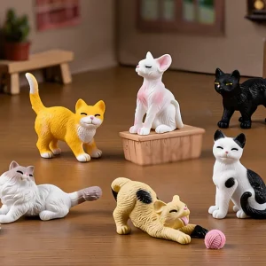 Mini cat figures including a stretching calico and fluffy white cat on wood.