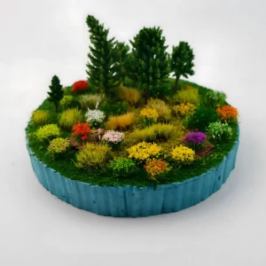 Red and yellow model flower clusters surrounding a miniature farmhouse with a vintage blue truck.