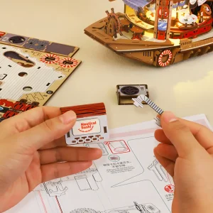 Hands assembling a Japanese sushi boat model kit part of a mechanical wooden puzzle for adults.
