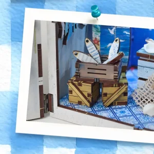Close-up of coastal miniature scene with tiny wooden fish crate on Mediterranean tiled floor.
