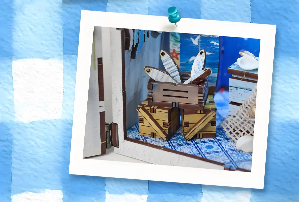 Close-up of coastal miniature scene with tiny wooden fish crate on Mediterranean tiled floor.