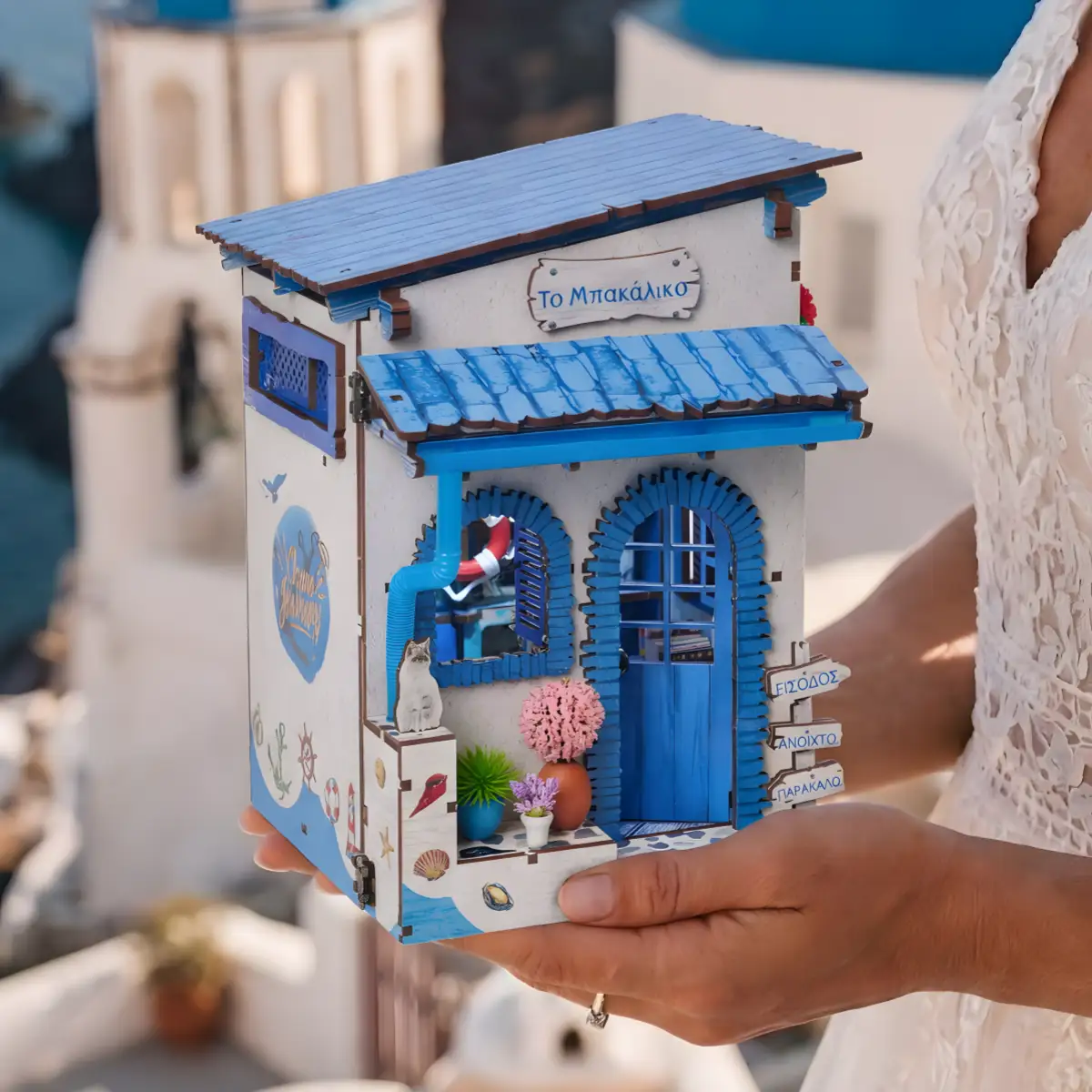 Close-up of a completed Santorini DIY book nook held gently against a coastal background.