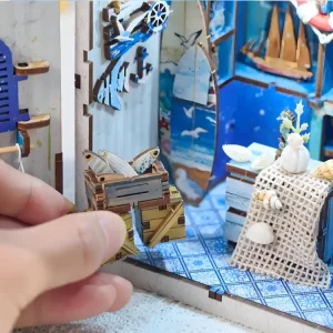 Hand placing a tiny wooden fish crate inside an immersive DIY book nook shop.