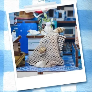 Miniature central table with fishnets and seashells inside the Greek seaside miniature house.