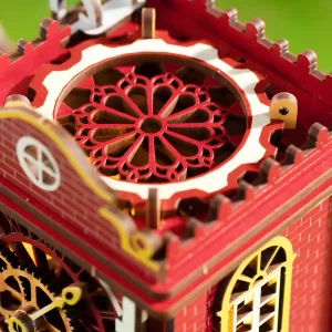 Intricate architectural wooden model detail showing the mechanical clock tower roof with red carvings.