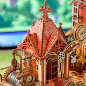 Architectural wooden model showing intricate rooftop shingle carvings and a rustic weather vane.