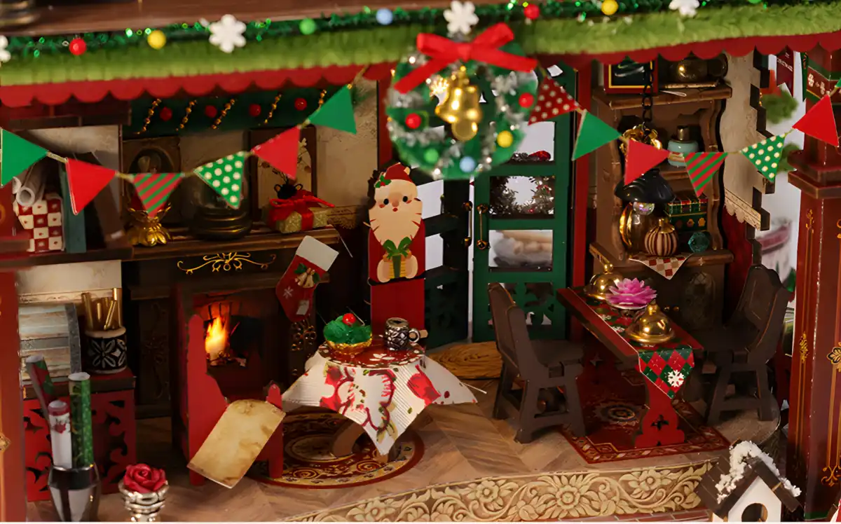 Cozy interior detail of Christmas cottage miniature with fireplace, dining set, and festive wreath decoration.