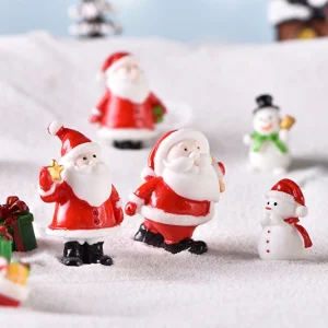 Snowy miniature Christmas village scene with Santa Claus figurines and small winter house