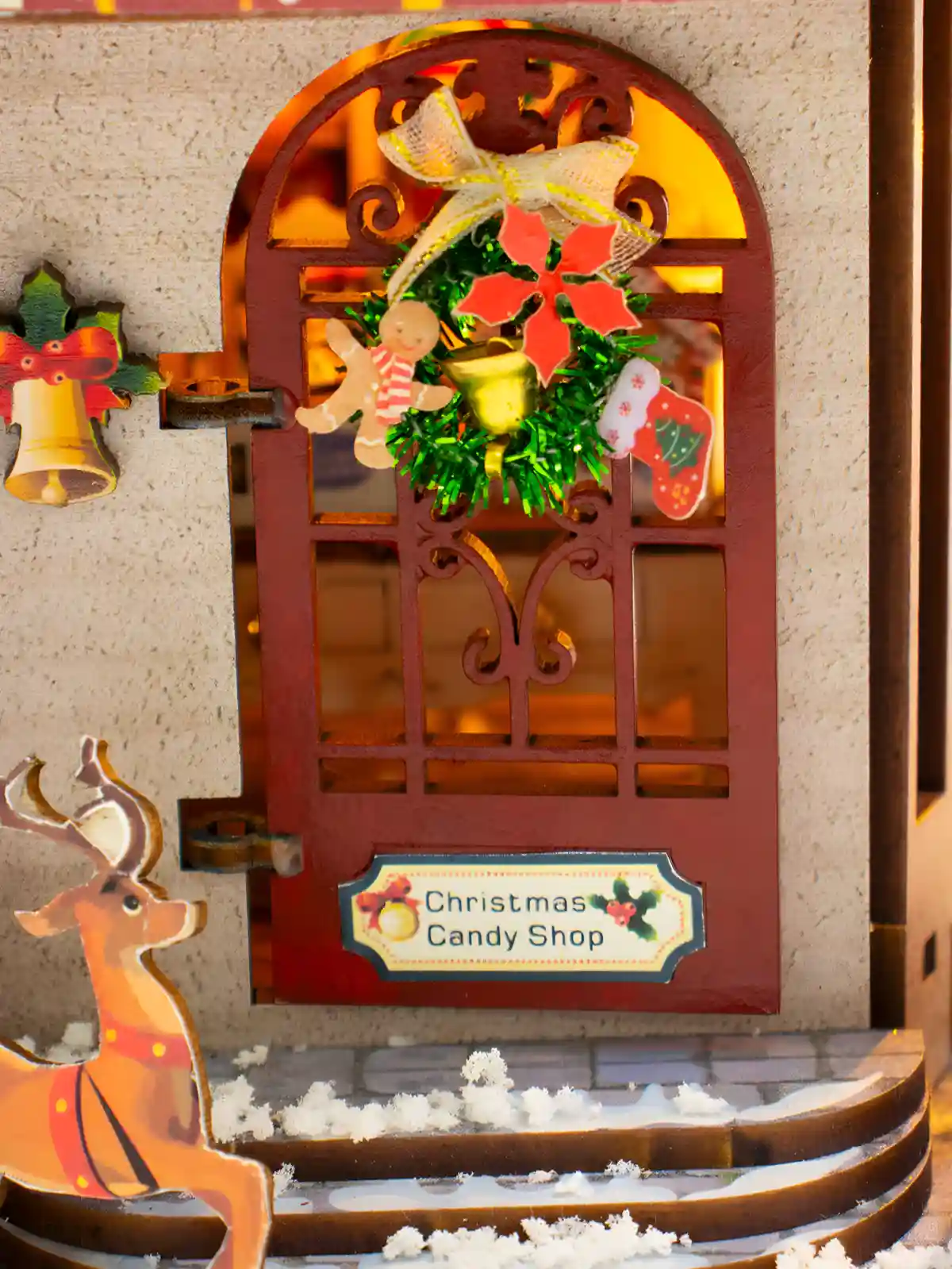 Front door of miniature candy shop adorned with festive Christmas wreath and reindeer