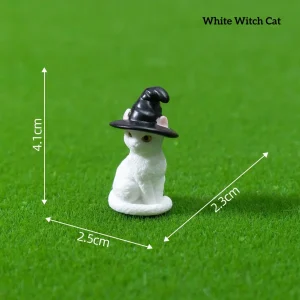 White cat wearing black witch hat fantasy miniature accessories on green grass