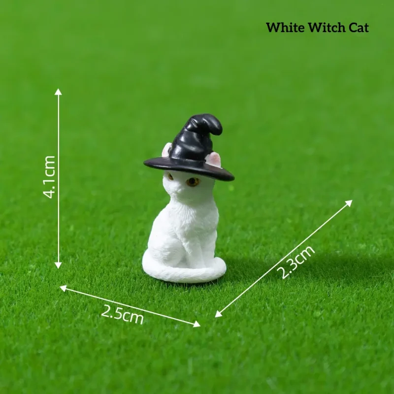 White cat wearing black witch hat fantasy miniature accessories on green grass